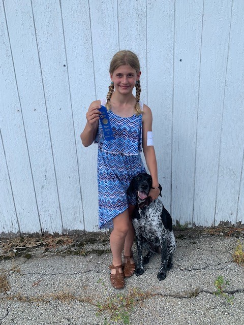 A Tailwaggers 4-H member posing with her dog and a blue ribbon.
