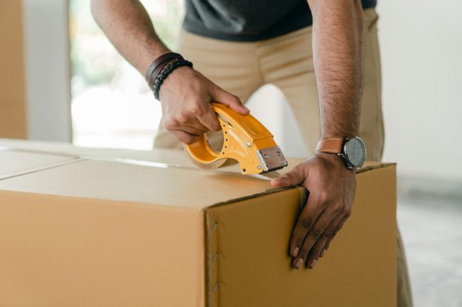 a person taping a moving box.